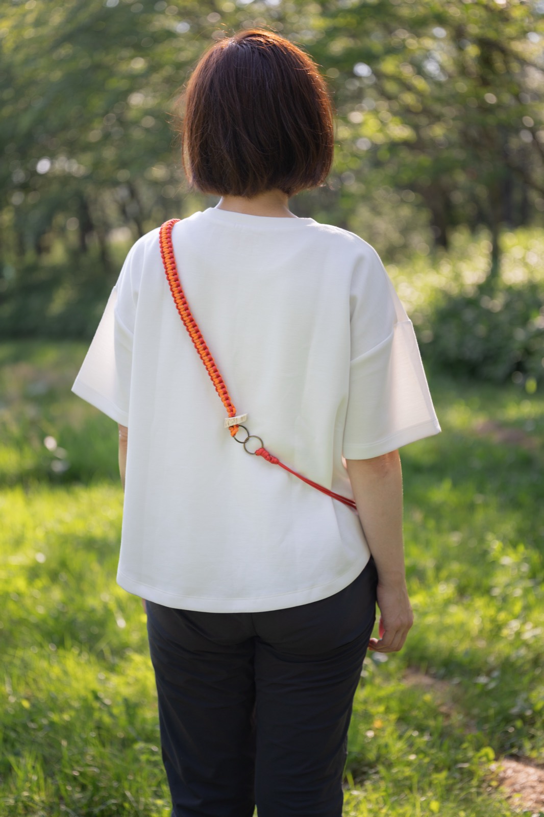 オレンジのストラップを斜めがけした後ろ姿